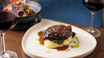 A plate of food with a meat dish and mashed potatoes, accompanied by a glass of red wine.