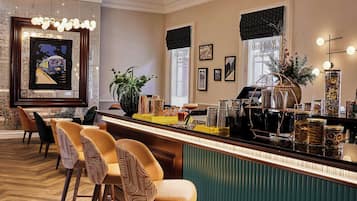 Eine Bar mit Schachbrettmuster-Boden, Barhocker, einer grünen Bar und einer Kronleuchter.