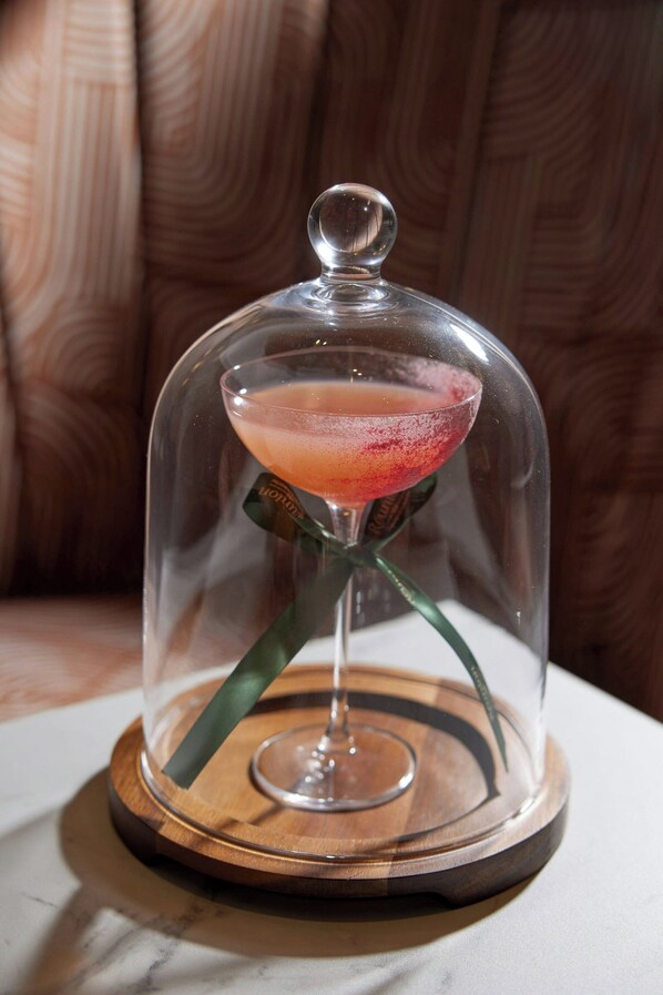 A cocktail under a glass dome on a wooden coaster. - The Clermont London, Victoria (London)