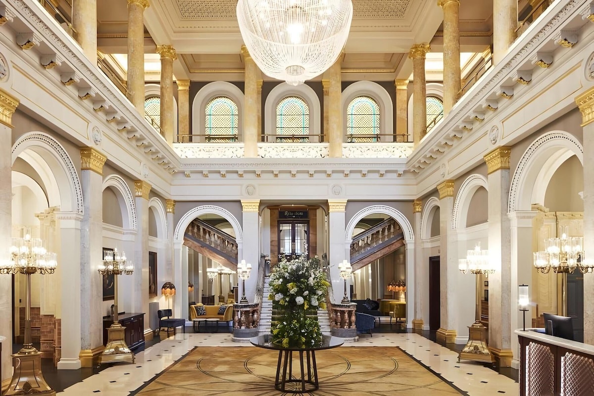 Een statige lobby met hoge plafonds, versierde zuilen en een grote kroonluchter.