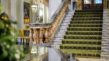 Un magnifique escalier avec des marches recouvertes d’une moquette verte et une balustrade en marbre.