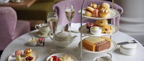 A tea service set with a tiered tray, teapot, cups, and saucers on a round table.