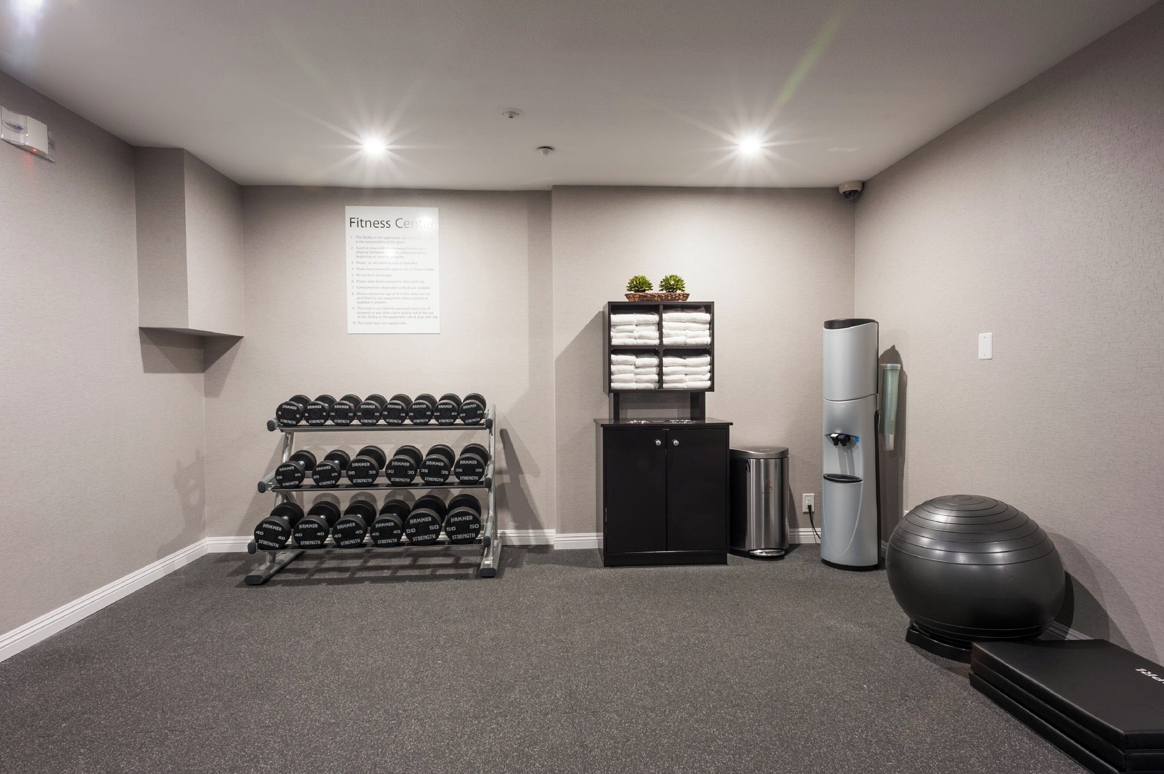 A fitness center with dumbbells, a water dispenser, and exercise equipment.