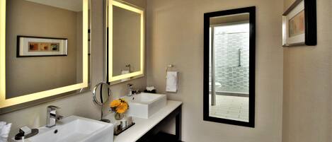 A modern bathroom with two sinks, a large mirror, and a window providing a view of the outside.