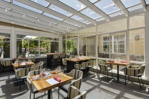 Ein Restaurant mit Glasdecke, Tischen und Stühlen und Blick ins Freie.