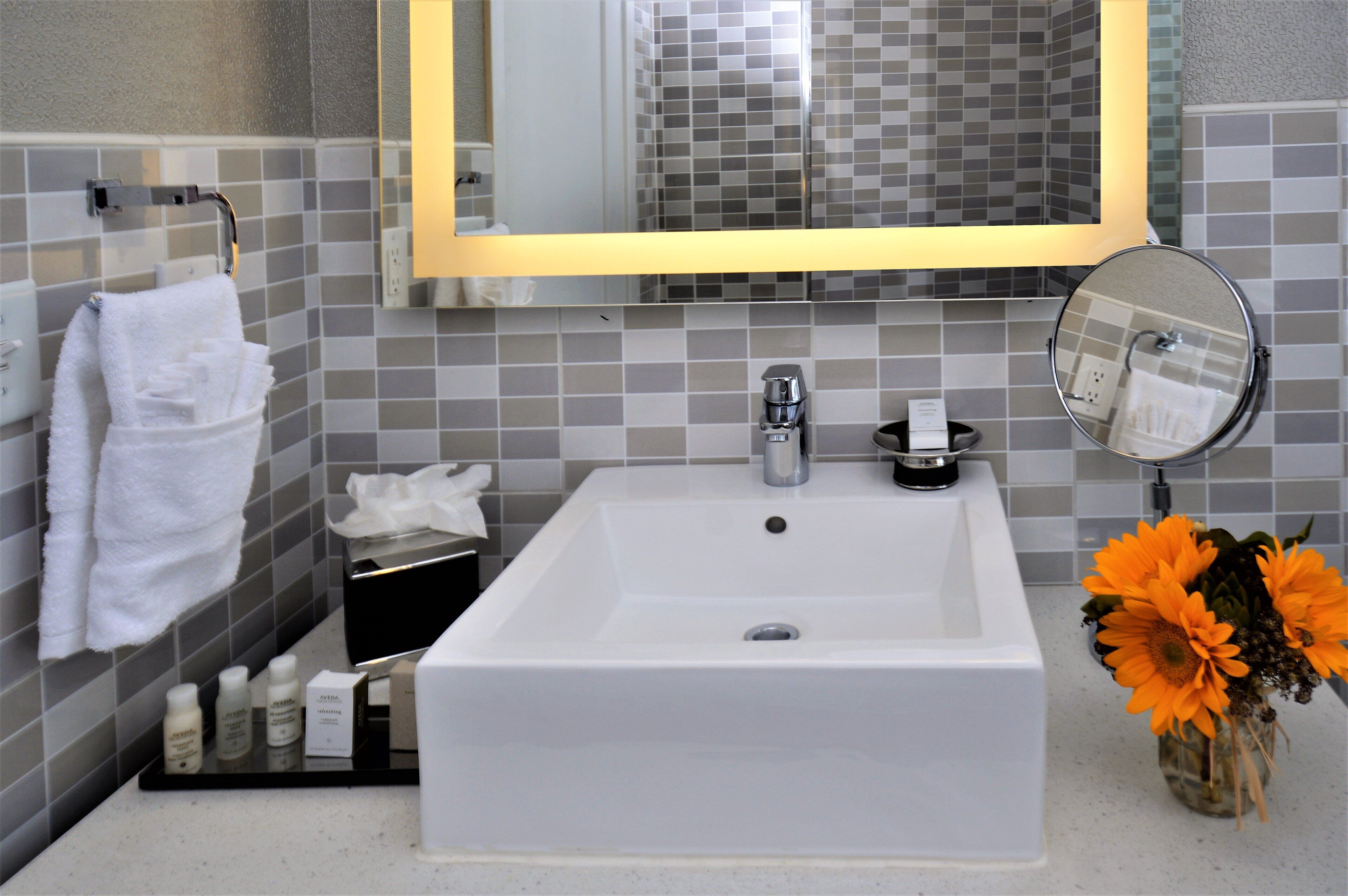 A bathroom with a white sink, a mirror, and a towel rack.