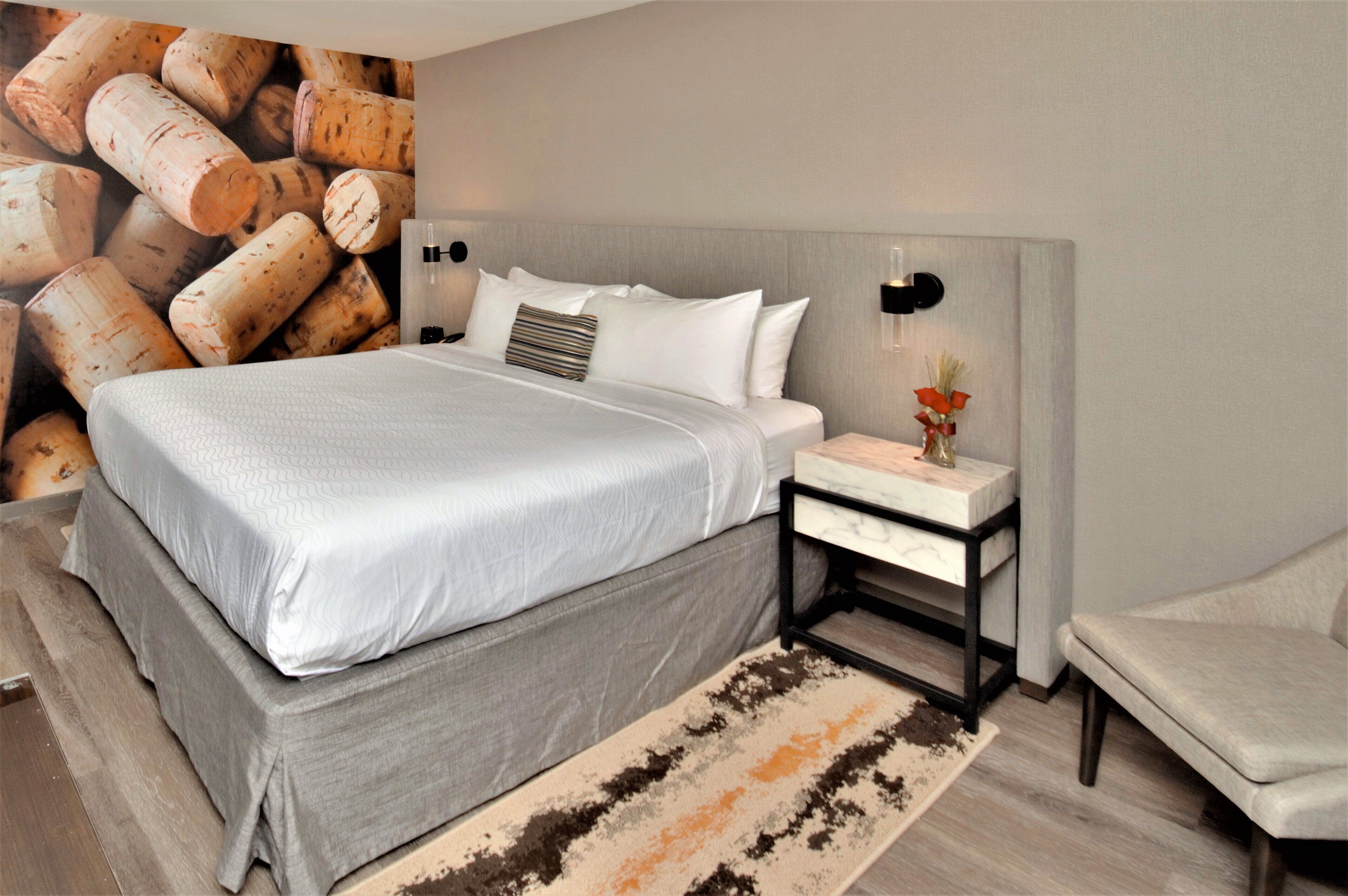 Un dormitorio moderno con una cama grande, una mesita de noche con un florero y una lámpara de pared.