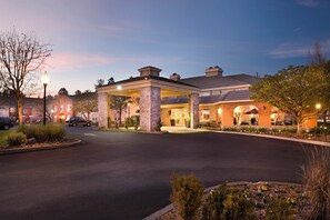 A hotel entrance with a covered driveway, stone pillars, and a landscaped area with plants. - Hotel Indigo Napa Valley by IHG (Napa)
