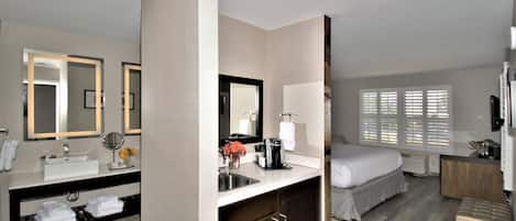 Une chambre d’hôtel avec une salle de bain, un lit, un bureau et une fenêtre.
