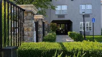 A building with a stone entrance, a van accessible sign, and a well-maintained hedge in the foreground.