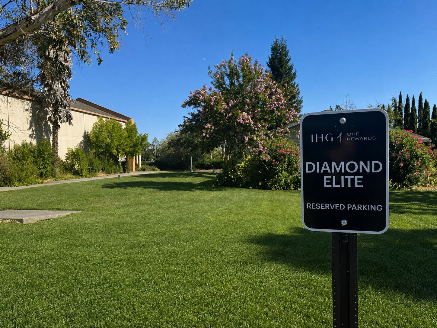 Een bord dat gereserveerde parkeerplaatsen aangeeft voor hotel 'Diamond Elite', met een heldere lucht en groen in de achtergrond.