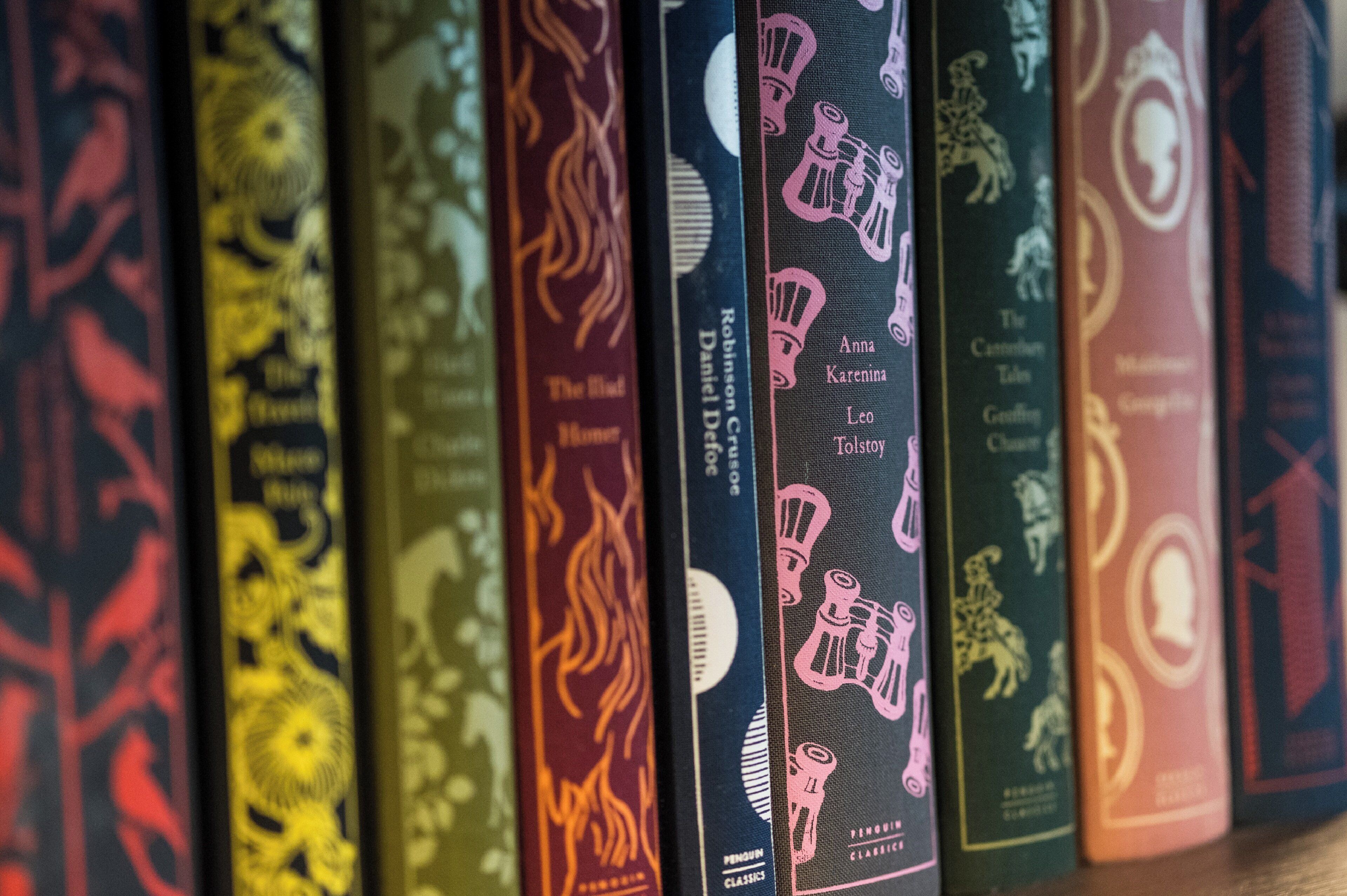 A row of books with various titles and authors on a shelf.