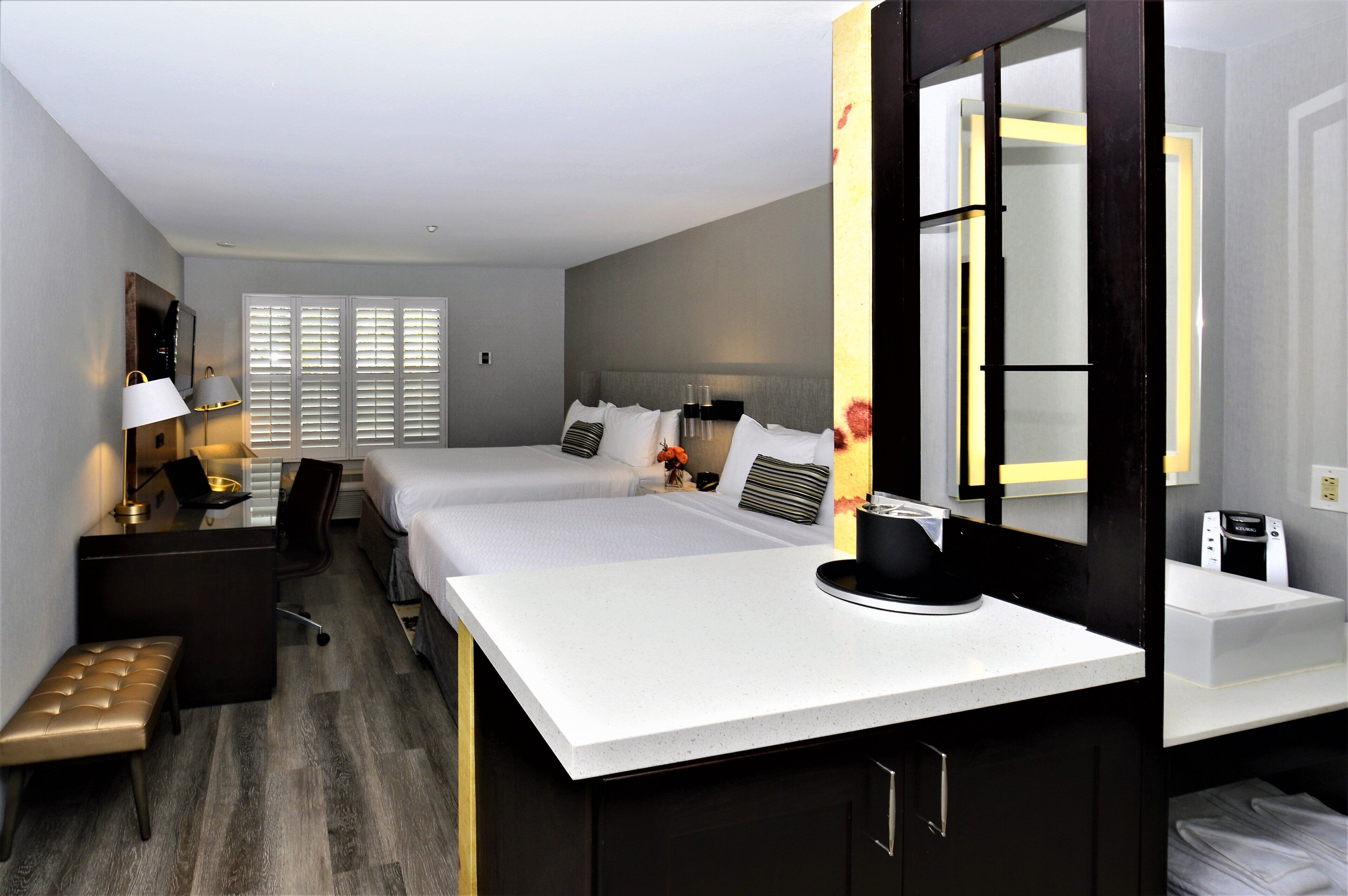 A hotel room with a bed, bedside table, lamp, and a coffee machine.