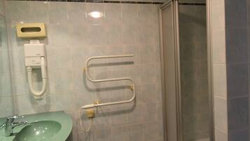Une salle de bain avec un lavabo vert, un distributeur de papier toilette, un sèche-mains et une cabine de douche en verre.