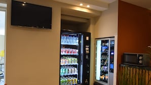 A hotel lobby with a vending machine, a flat-screen TV, and a seating area. - Sleep & Go Brussels Expo (Grimbergen)