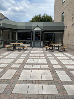 A courtyard with a central entrance, surrounded by tables and chairs.