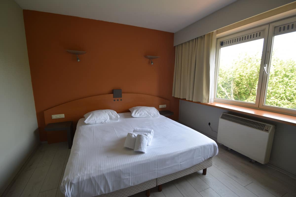 A neatly made bed with white linens, a headboard, and two bedside tables with lamps.