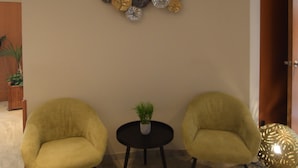 A room with two yellow armchairs, a small round table with a plant, and decorative wall art. - Sleep & Go Brussels Expo (Grimbergen)