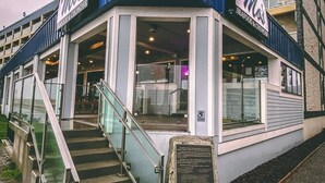 Un restaurante de mariscos con fachada azul, entrada de cristal y una escalera que lleva a la entrada.