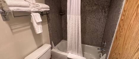 A bathroom with a bathtub, toilet, and shower curtain.