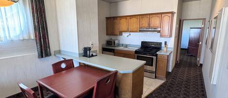 A compact kitchen with wooden cabinets, a microwave, a stove, and a dining area with a table and chairs.