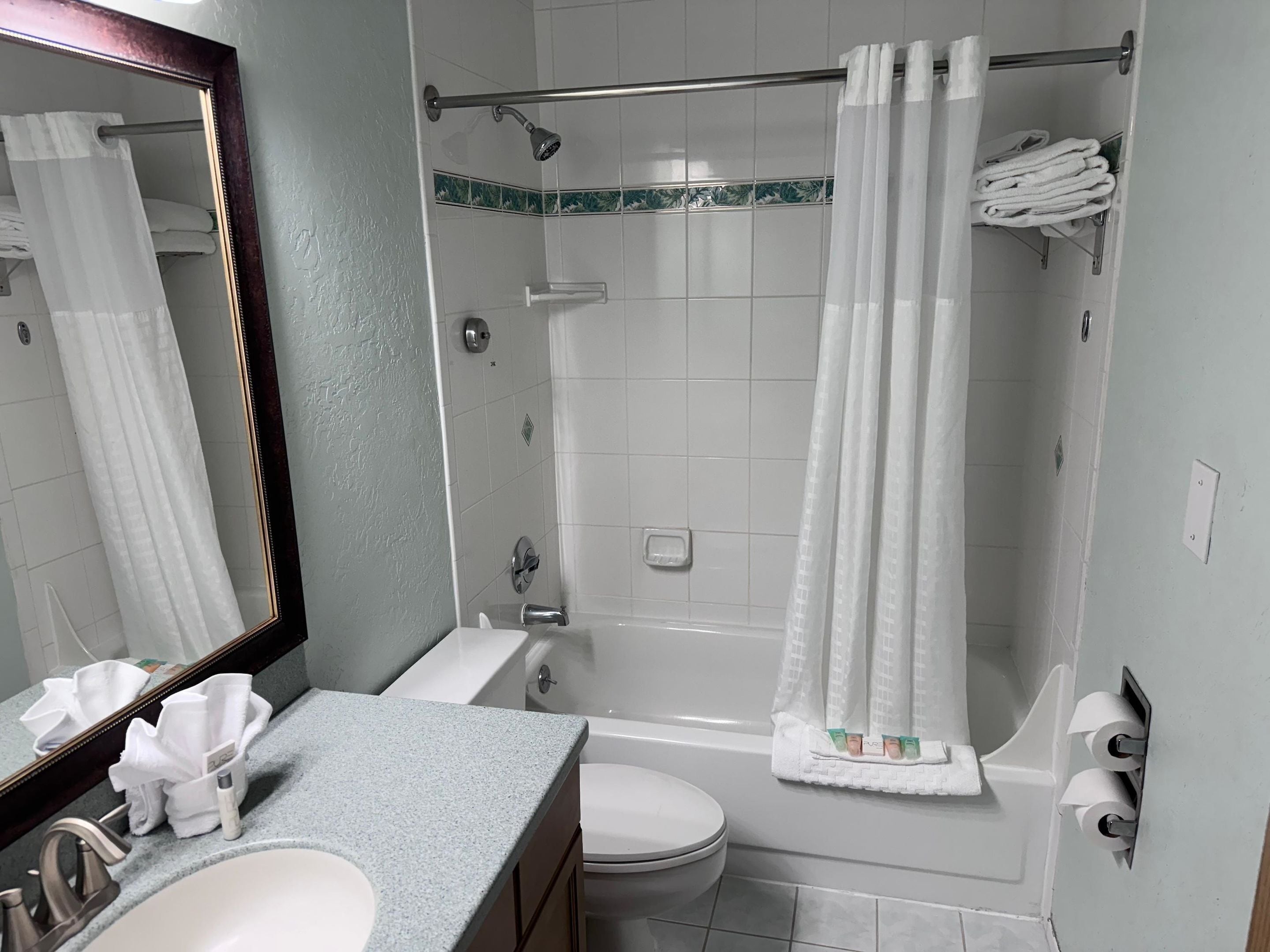 A bathroom with a bathtub, toilet, sink, and a mirror.