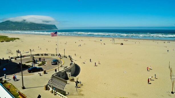 Una playa con una bandera, gente y una carretera.