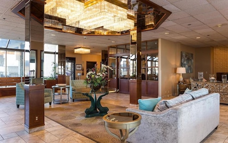 A spacious lobby with a chandelier, seating area, and a large window.