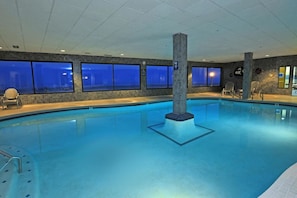 An indoor swimming pool with clear blue water, tiled walls, and windows. - Promenade Inn & Suites Oceanfront (Seaside)