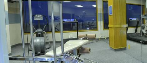 A medical examination room with a treadmill, exercise bike, and a large window.
