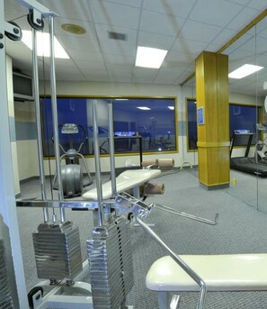 A medical examination room with a treadmill, exercise bike, and a large window. - Promenade Inn & Suites Oceanfront (Seaside)