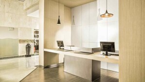 A modern reception area with a long counter, two monitors, and pendant lighting. - Asyana Kemayoran Jakarta (Jakarta)