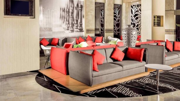 A modern lobby with a grey sofa, red cushions, and a large abstract artwork on the wall. - Asyana Kemayoran Jakarta (Jakarta)