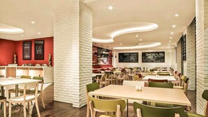 A modern restaurant with multiple dining areas, white brick walls, and wooden tables and chairs. - Asyana Kemayoran Jakarta (Jakarta)