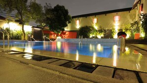 A swimming pool at night with surrounding buildings and trees. - Asyana Kemayoran Jakarta (Jakarta)
