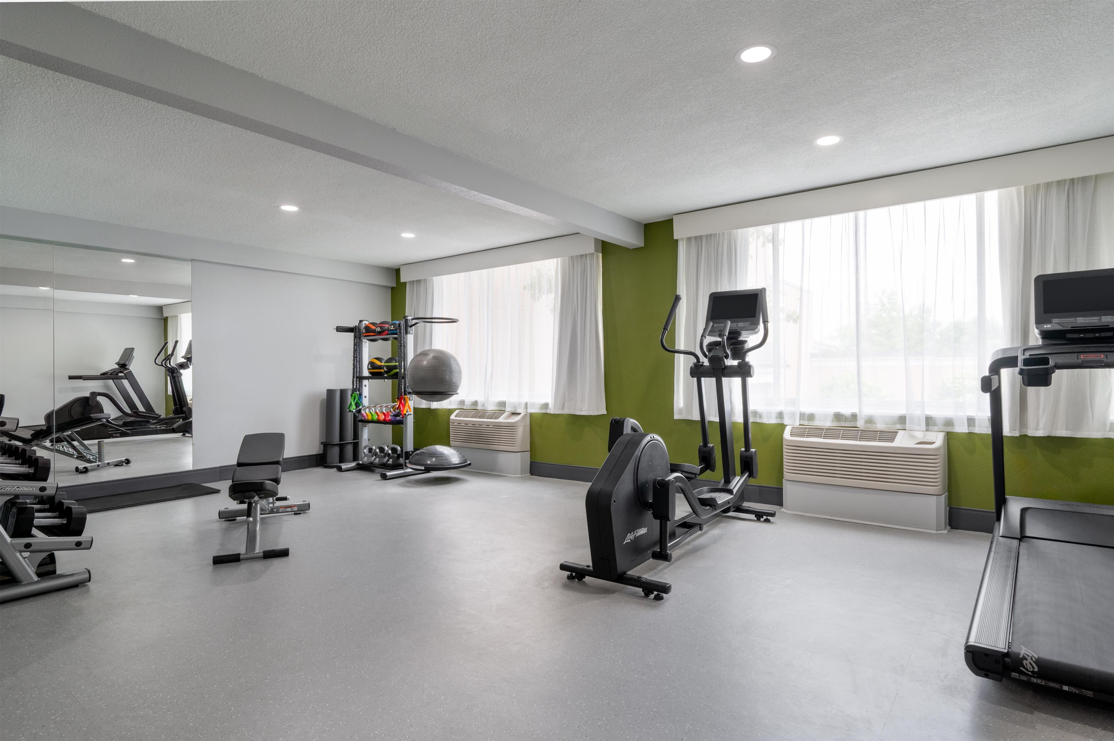 A gym with various exercise equipment, including treadmills, a stationary bike, and free weights.