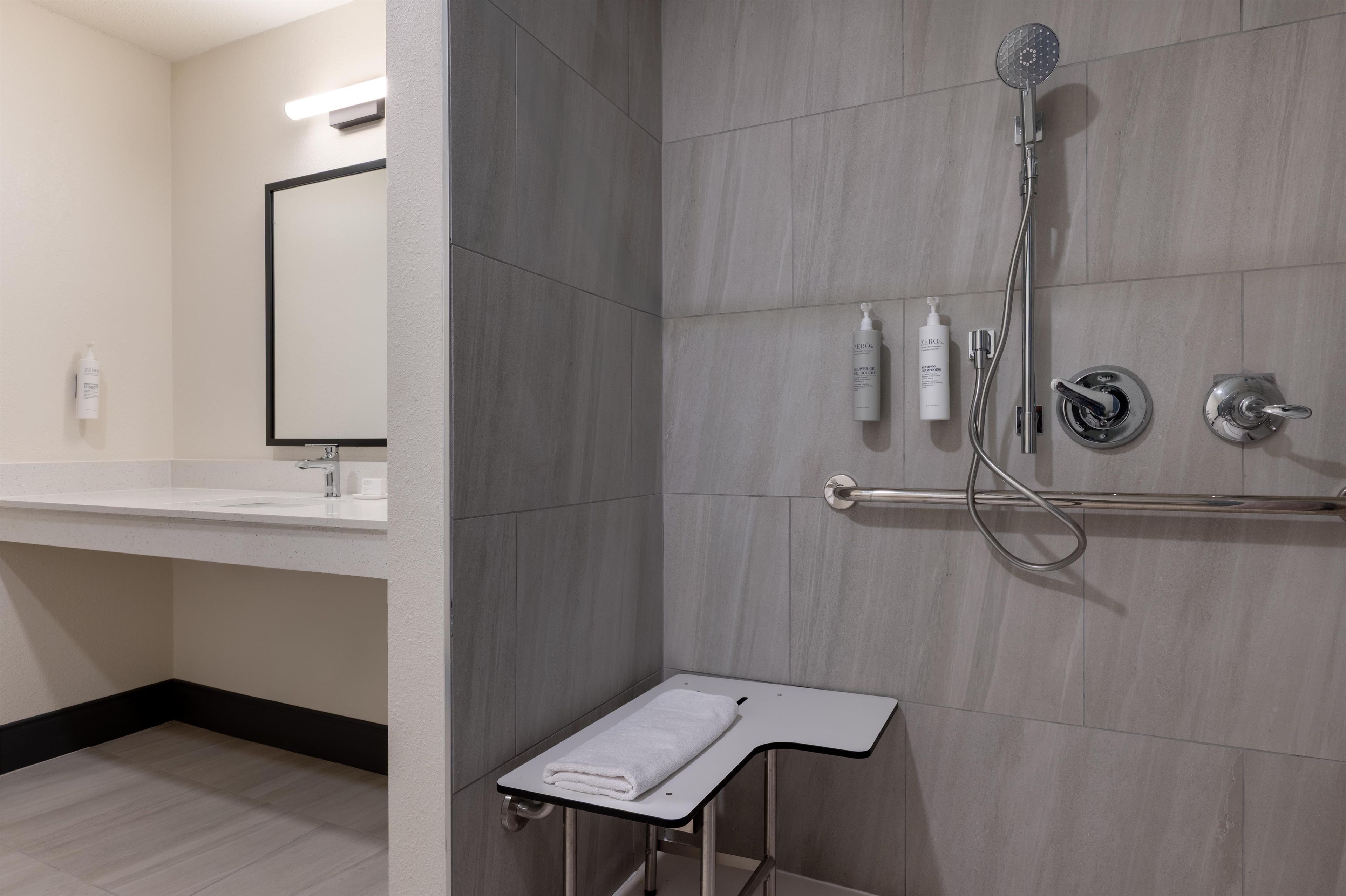 A modern bathroom with a shower, a sink, and a towel rack.