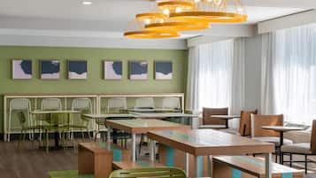 A modern dining area with a long communal table, individual tables, and chairs.