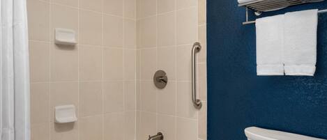 Un baño con bañera, inodoro, ducha y un perchero con toallas.