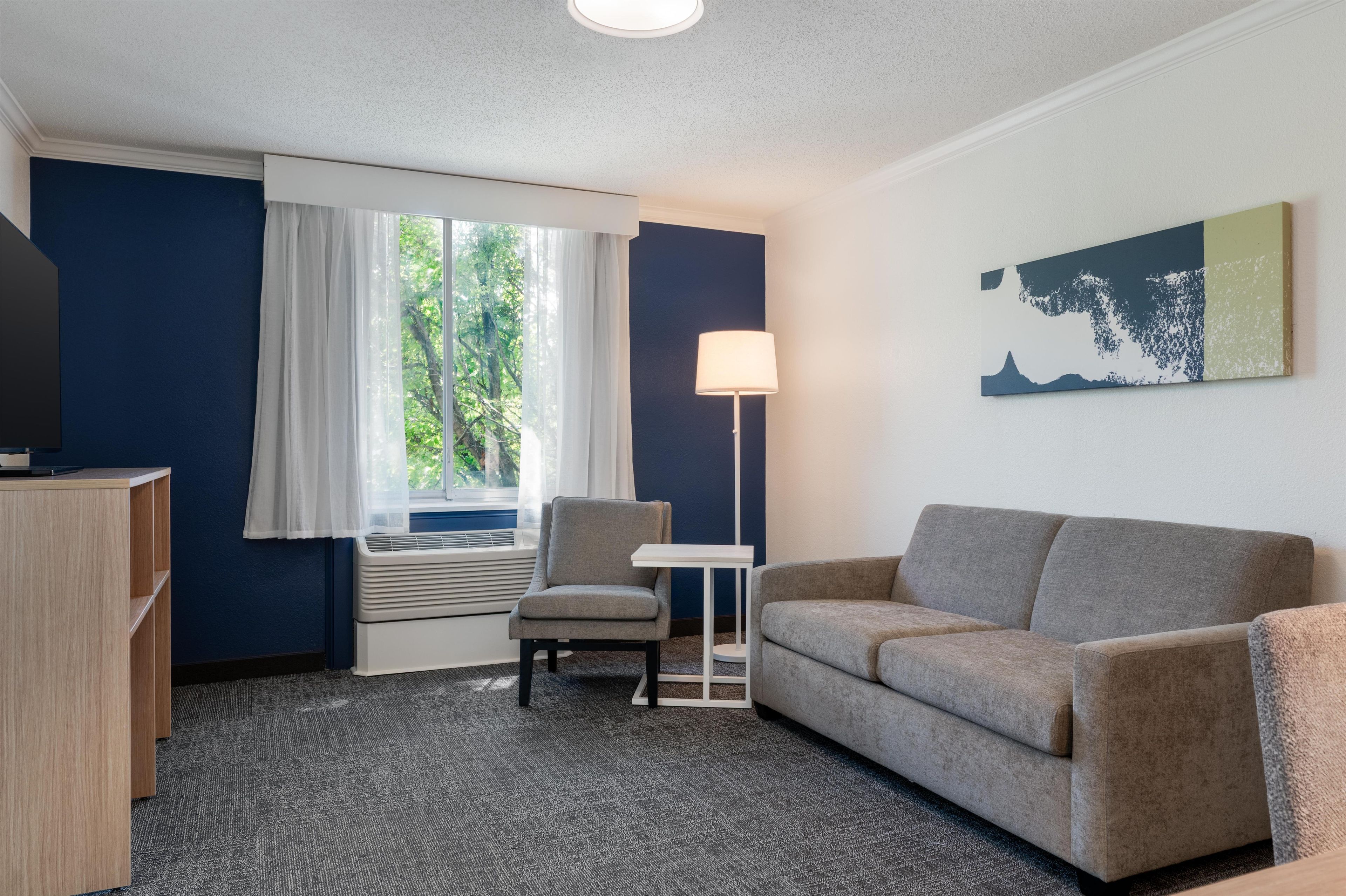 Hotellihuone, jossa on sohva, nojatuoli ja pieni pöytä.