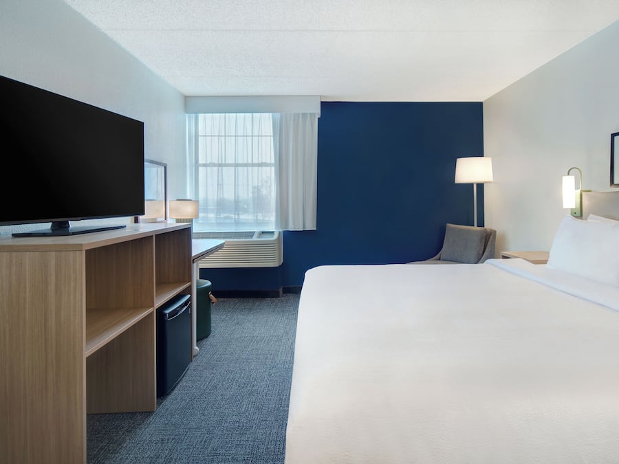 Une chambre d’hôtel avec un lit, une télévision, un bureau et une fenêtre.