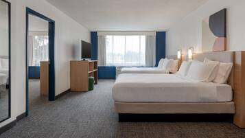 Une chambre d’hôtel avec un grand lit, une télévision, un bureau et une fenêtre avec des rideaux.