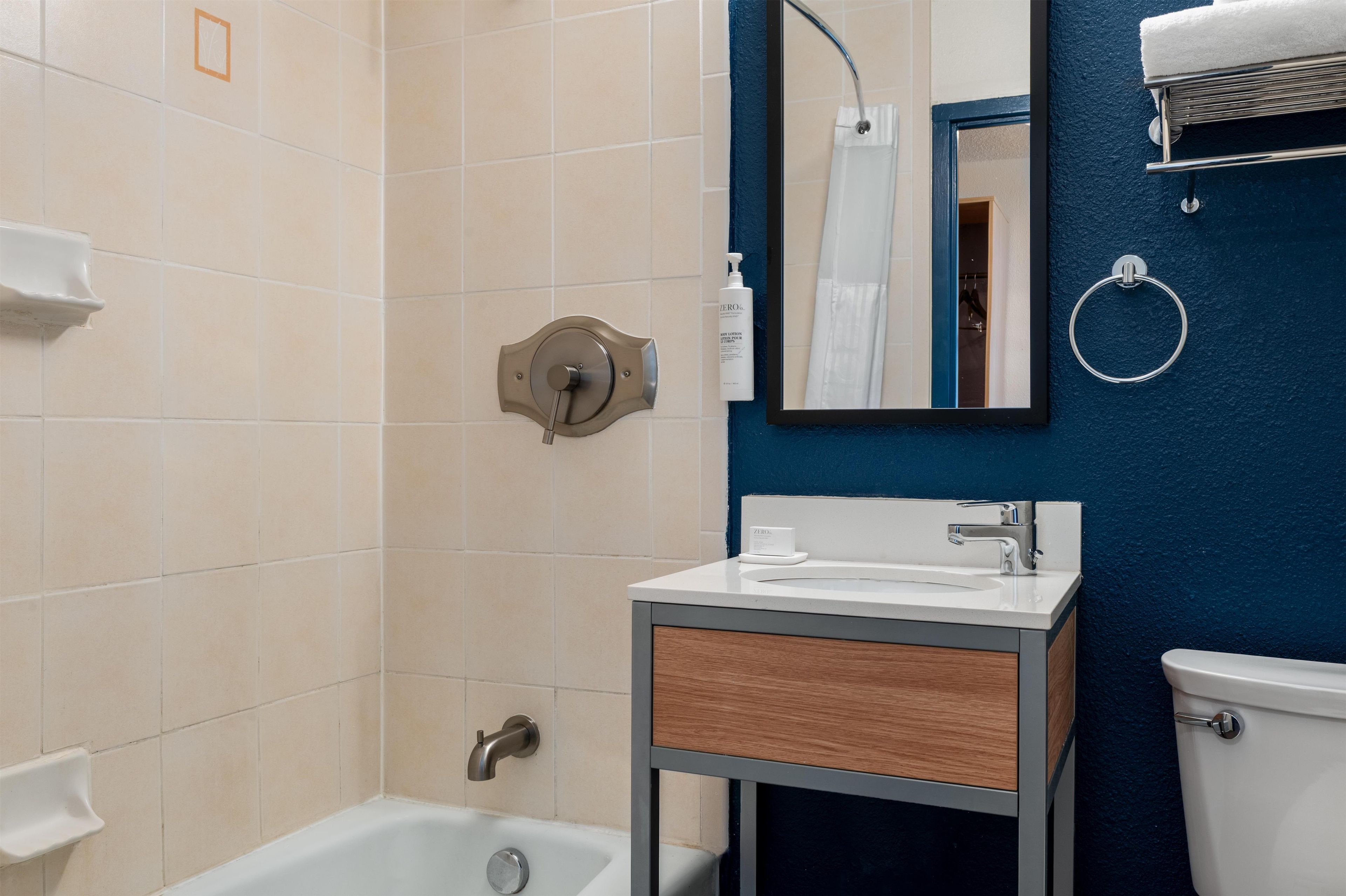 A bathroom with a bathtub, a sink, a mirror, and a towel rack.