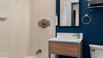 A bathroom with a bathtub, a sink, a mirror, and a towel rack.