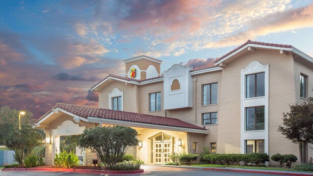 A hotel with a traditional architectural style, featuring a central entrance with a covered porch, multiple windows, and a tiled roof. - Super 8 by Wyndham Austell/Six Flags (Austell)
