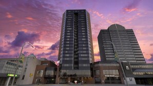 A tall building with a modern design, a restaurant named 'River Room' at the base, and a distinctive logo on the facade. - Best Western Plus Waterfront Hotel (Windsor)