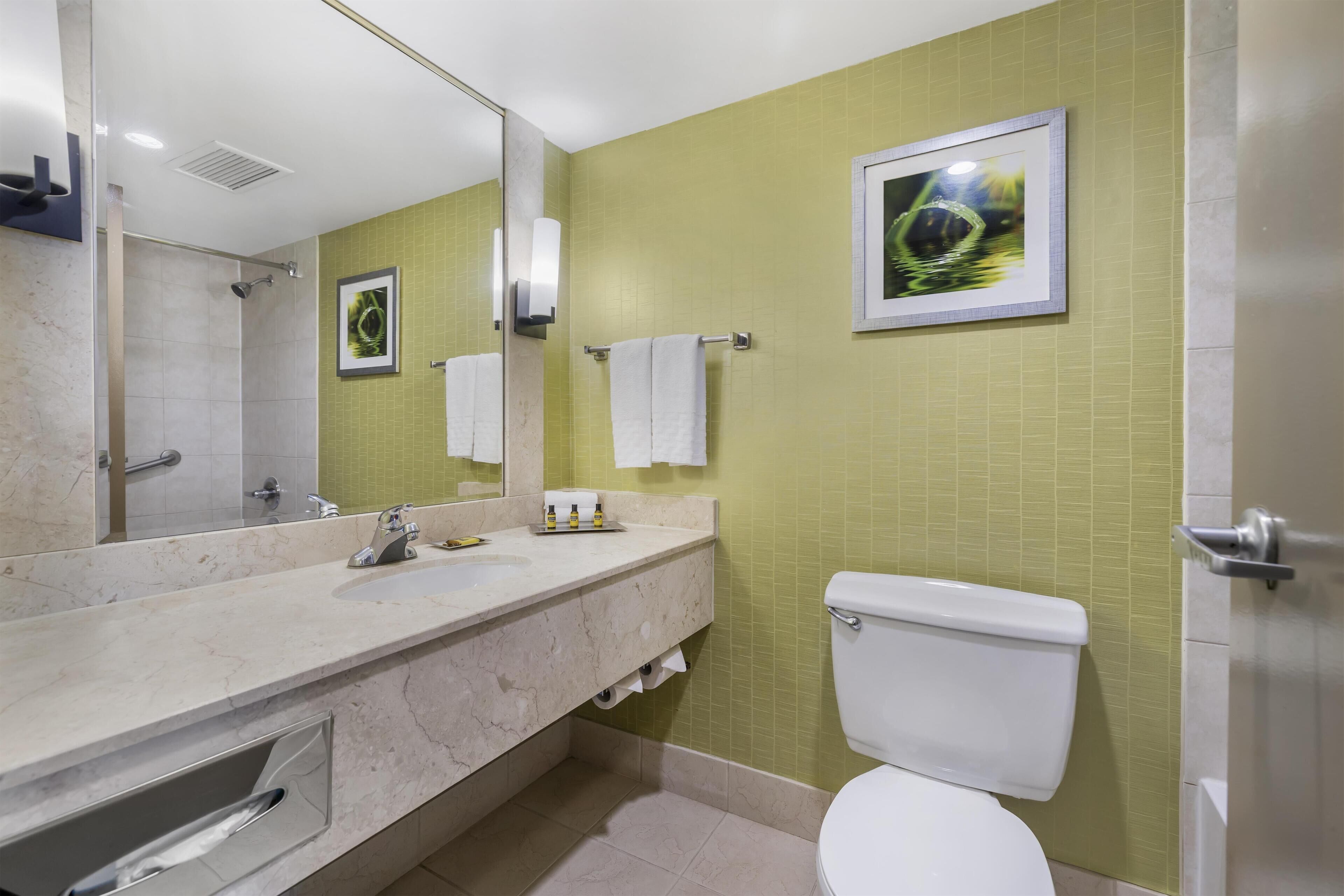 A modern bathroom with a marble sink, a toilet, and a shower.