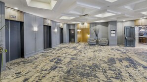 A spacious hotel lobby with a patterned carpet, a seating area with chairs, and a reception desk. - Best Western Plus Waterfront Hotel (Windsor)