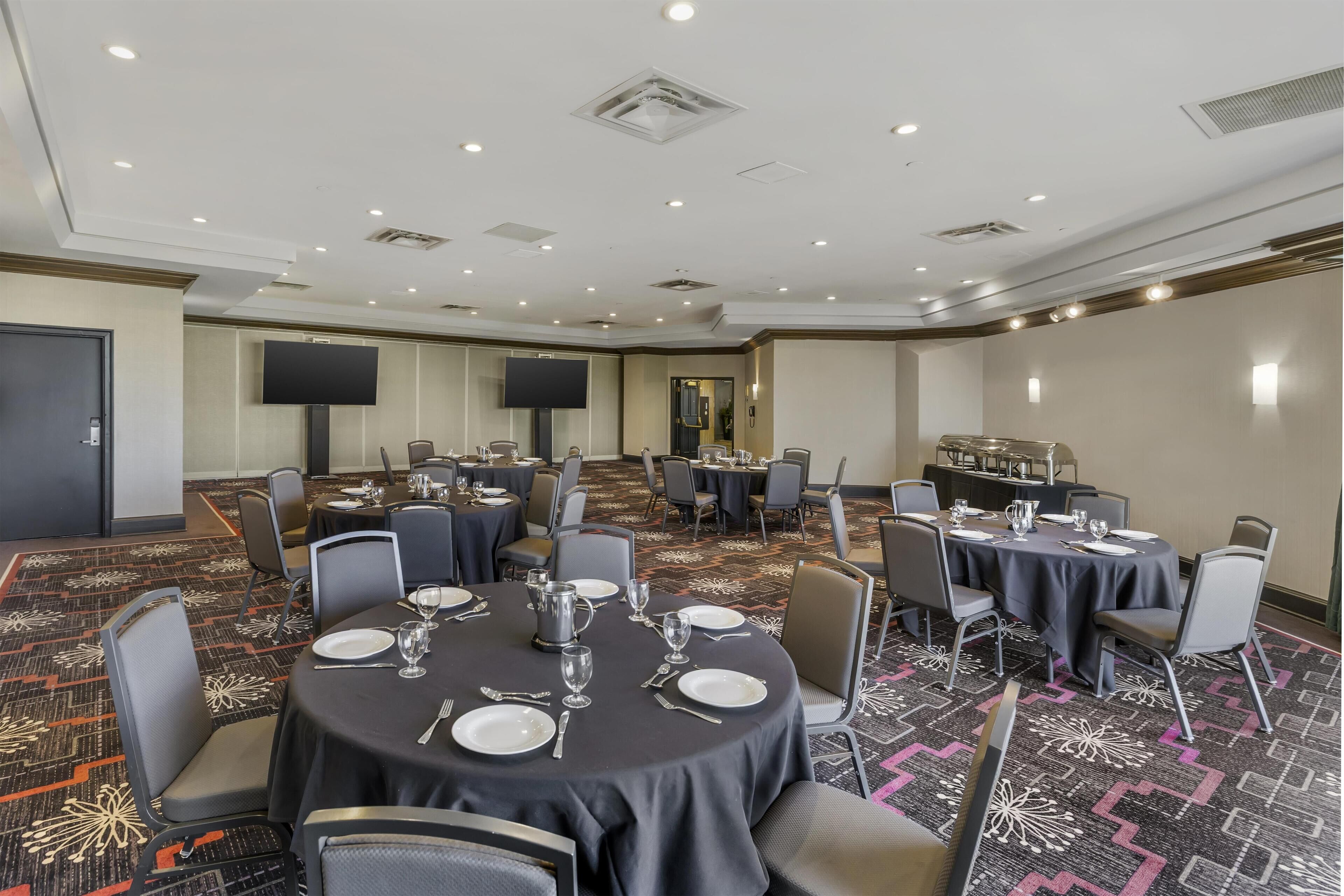 A conference room with round tables, chairs, and a large screen.