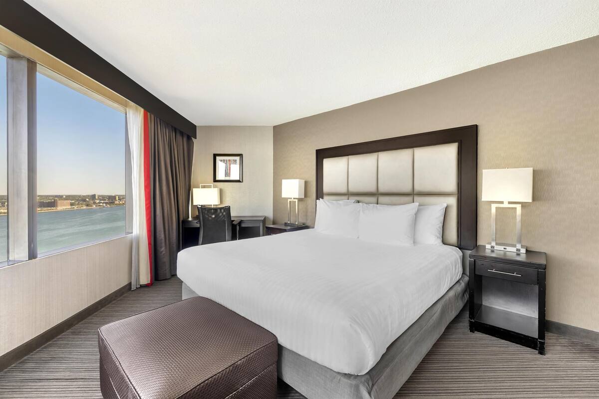 Habitación de hotel con una cama grande, un escritorio y vista al agua.